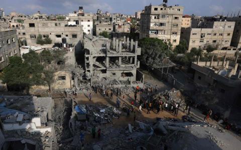 星期天凌晨，以色列猛烈轰炸加沙地带，加沙南部城镇拉法也被击中，图为当地居民聚集在被炸塌的建筑物前。（法新社）