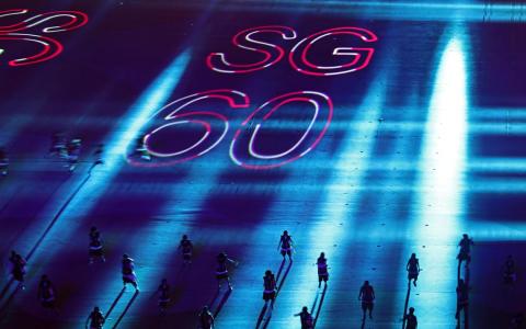 政府大厦前大草场的表演舞台地面上投影“SG60”灯光，为新加坡60岁生日增添喜庆色彩。（陈渊庄摄）