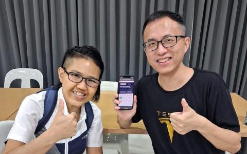 在教育部工作的吴婉君（左）上个月两度到民众俱乐部协助国人兑换邻里购物券。（社区发展理事会提供）