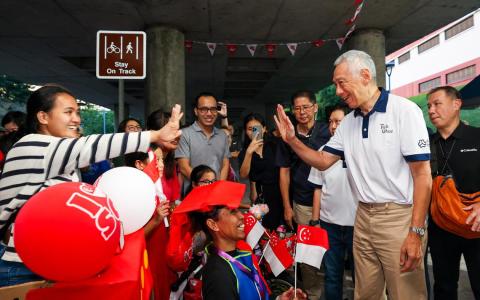 国务资政李显龙（前排右一）为德义区SG60嘉年华致辞时说，只要国人齐心协力、彼此信任，并以一个民族、一个国家的姿态共同前进，新加坡就能变得更好，不仅造福这一代人，也让子孙后代在未来许多年都受益。（林明顺摄）