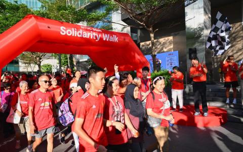 1500人参加职总举办的SG60齐心健行活动，筹获近300万元协助低收入会员和家属。职总秘书长黄志明（右二）和会长丹娜乐芝米（右三），星期六早上在职总总部为活动挥旗。（海峡时报）