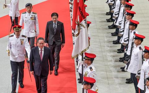 中国总理李强（前排左二）星期六（10月25日）抵步后，在国会大厦出席黄循财总理（后排左二）为他举行的欢迎仪式，两人一同检阅仪仗队。（陈渊庄摄）