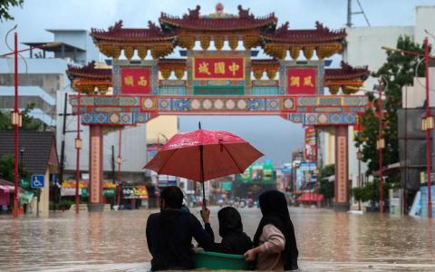 泰国南部宋卡府合艾遭暴雨袭击，人们趟过被洪水淹没的街道。（路透社）