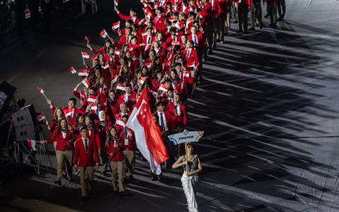 出席开幕式的我国代表团共有112人，羽毛球“一姐”杨佳敏（举新加坡国旗者）和巴西柔术选手林天润（杨佳敏右侧、戴蓝领带者）是擎旗手。（白艳琳摄）