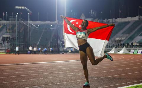 成功卫冕的珊蒂，赛后在曼谷国家体育场的跑道上高举新加坡国旗绕场庆祝。（白艳琳）