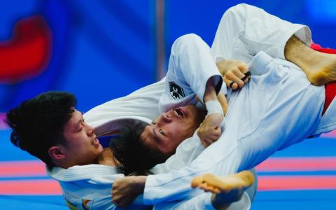 我国选手林天润（左）在混合团体赛以决定性的降服技战胜泰国选手。（新加坡体育理事会提供）