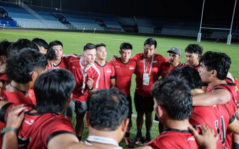 我国主教练蒂杰恩斯（左中握拳者）赛后感到无比自豪，他在曼谷皇家泰国空军体育场中央鼓励全队继续向前。（卓舒畅摄）