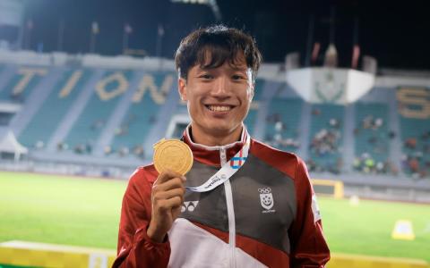 凭借顽强意志力率先冲线的郭俊杰，赛后为新加坡和自己举起了一枚沉甸甸的金牌。（海峡时报）