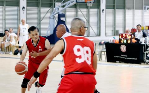 12月27日，新加坡篮球中心引爆的新加坡篮球百年发展一压轴友谊赛，群友队的74岁球员柯文辉（左一）在场上以行云流水之势，控球突破通淮队防守队员。（邝启聪摄）