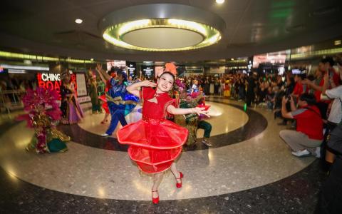 身着不同种族特色服饰的2026妆艺大游行演出者，2月8日在海湾舫地铁站等地和公众互动。图为身着灯笼状喜庆服饰的表演者，在地铁站大量围观人群中翩翩起舞。（陈渊庄摄）