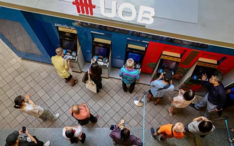 星期三立春这一天，大巴窑中心的大华银行存提款机前排起长队，有人领新钞，有人存现金，为新一年讨个好意头。（陈斌勤摄）