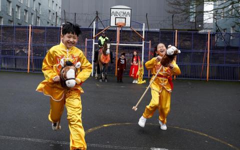 在爱尔兰都柏林这个社区中心，小朋友在学校操场上骑着木马赛跑，为马年的到来增添年味，骑着马的骑警也参与了活动。（路透社）