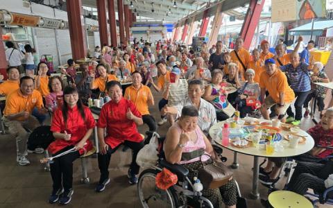 众弘福利社义工与长者们，在大巴窑的小贩中心共享新春午餐。（众弘福利社提供）