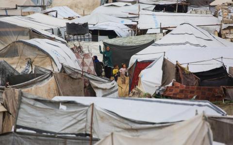 4月1日，加沙地带南部汗尤尼斯市纳赫尔巴雷德地区的一个临时巴勒斯坦流离失所者营地，一名妇女看着孩子们在帐篷间玩耍。（法新社）