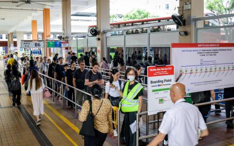 地铁环线列车服务星期天（4月12日）早上延迟至9时才开始，受影响的乘客在巴士转换站耐心排队等候接驳巴士，现场安排了身穿荧光绿背心的工作人员协助指引乘客，维持秩序。（叶振忠摄）