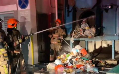 事发照片显示，至少有三名新加坡民防部队人员到场救援，并利用一支水枪对准垃圾压缩机的出口喷水。（取自Singapura Channel脸书）