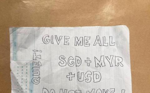 证物照片显示，字条应该是从记事本撕下的一页纸，上面写着“安静，别动，把所有新元、令吉和美元交给我”。（新加坡警察部队提供）