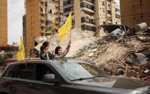 以色列连日袭击真主党控制的贝鲁特南部郊区，逾100万人流离失所。以黎停火4月17日生效后，两名女孩挥舞着真主党旗帜，乘车返回贝鲁特南部的家园。 （路透社）