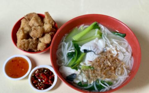 安顺海鲜汤的粗米粉黑白鱼片汤，摊主贴心地把炸鱼与汤分开盛放，避免浸泡影响口感。（叶晓虹摄）