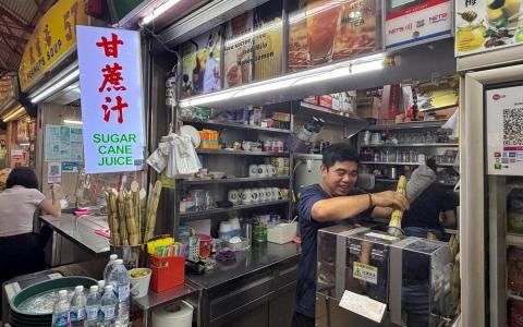 在麦士威小贩中心经营饮料摊的郑镜宝三年前在清洗榨甘蔗机时，不慎左掌被卷入。复原后，他继续经营摊位，也开始重新榨甘蔗。（黄宇璇摄）