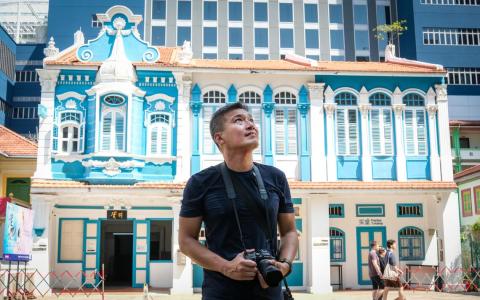 陈威仁在滑铁卢街上考察拍摄，背景为实践剧场。（曾坤顺摄）