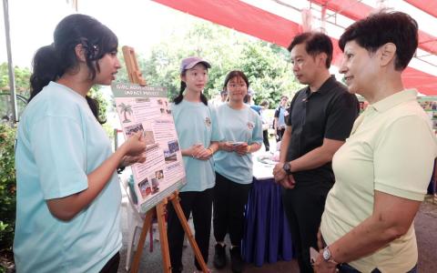女童军义工萨米哈（左一）和黄欣怡（左二）向国家发展部兼贸工部政务部长陈圣辉（右二）与总理公署部长兼财政部及国家发展部第二部长英兰妮（右一）介绍她们的斐济学习之旅。这两名女生说，乌敏岛学校倡议给了她们宣导可持续性的平台。（郑一鸣摄）