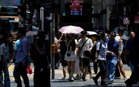 香港正式进入夏季流感季节，冠病病毒活跃程度也持续上升。图为香港市民在夏季烈日下出行，摄于6月22日。（香港中通社）