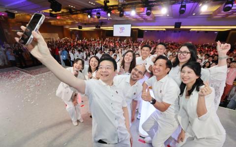 人民行动党星期六庆祝成立40周年。行动党秘书长、总理黄循财致辞后，拿起手机与青年团主席、国家发展部兼贸工部政务部长陈圣辉（第二排左二），以及在上一届大选中当选的行动党支部主席自拍合影。第二排左起是国家发展部兼教育部高级政务次长赛义德哈伦、陈圣辉及吕思憓；第三排左二起是陈以君、李蕙莹、蔡引舟、许德财及何礼娜。这场活动由本地网红李安（第三排左一）主持。（唐家鸿摄）