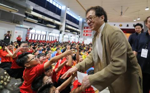 成龙亲切地和公立培群学校的学生们互动。（张俊杰摄）