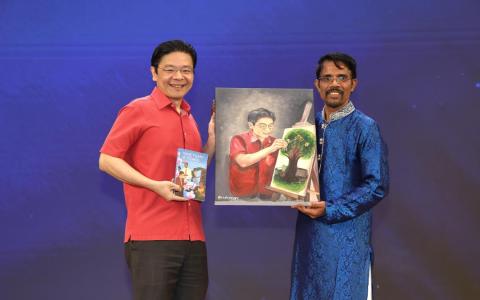 淡米尔文教师工会会长达纳帕尔古玛（右）赠送一幅画作，以及一本记载工会发展历程的新书给黄循财总理（左）。画作描绘黄总理在晚宴开始前，为庆祝工会成立75周年的纪念画作添上最后一笔的情景。（梁麒麟摄）