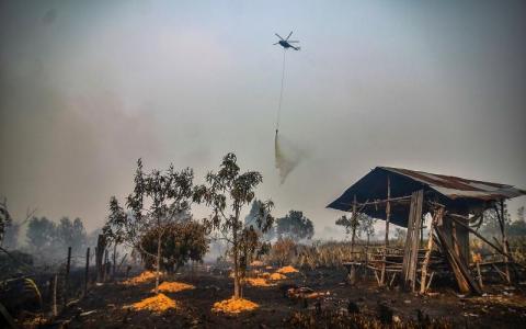 为了扑灭林火、赶走烟霾，一架直升机前天在廖内省甘帕区（Kampar）的一个泥炭起火地带投下水弹灭火。（法新社）