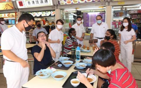 　当选西海岸区议员的人民行动党团队李智陞（白衣者左起）、胡美霞、洪维能、易华仁和王心妍昨早走访直落布兰雅熟食中心，答谢选民的支持。（庄耿闻摄）