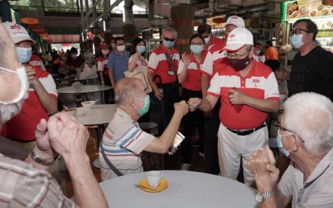 　陈清木医生（右二）昨早率领该党西海岸团队走访选区谢票。在“老家”亚逸拉惹的一座熟食中心，用餐居民纷纷与陈清木“碰拳”，或竖起大拇指向他比赞。（特约张荣摄）