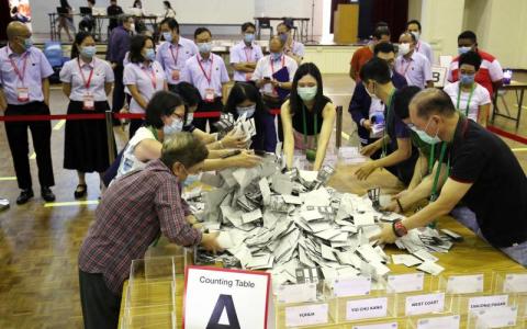 选举官员在各政党代表见证下，把不同站点的海外选票掺在一起，然后开始点算。（李健玮摄）