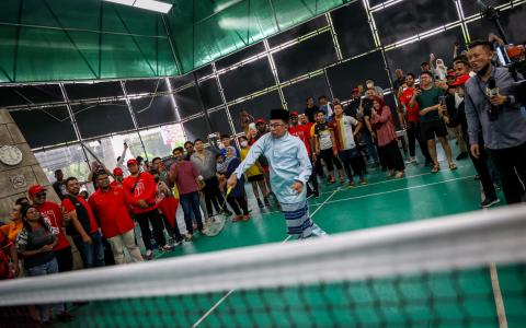 安华在投票日前一天卯足全力冲刺，从早到晚在霹雳出席12场造势活动，首站来到羽球场与选民切磋球技。（叶振忠摄）