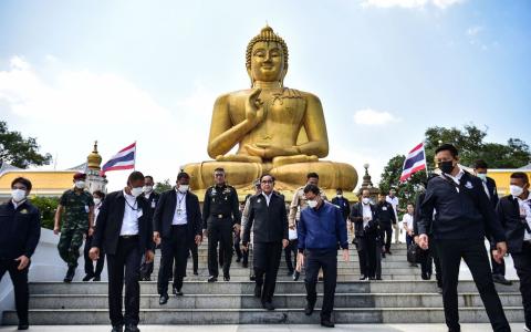 首相巴育（中）星期五宣布解散国会准备大选。图为巴育星期三（15日）访问泰南那拉提瓦府一座寺院。（法新社）