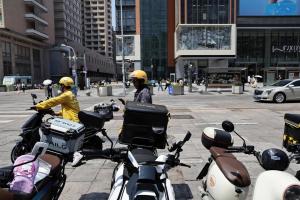 最新报告显示，中国外卖骑手数量去年增长6%，达到1590万人。图为今年6月，两名外卖骑手在北京王府井步行街附近工作。（海峡时报）