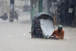 7月8日，孟加拉吉大港灾区一名人力车夫在洪水淹没的街道艰难前行。（AFP）