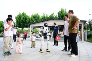 中国31个省市区今年上半年经济成绩单出炉，安徽首次超越湖南，跻身地区生产总值（GDP）10强省份。图为7月15日安徽省会合肥市民在“机器人9N中心”与一款人形机器人互动。（新华社）