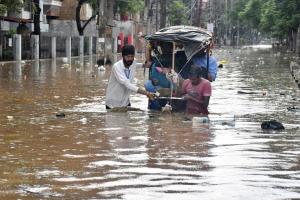 8月4日，印度阿萨姆邦古瓦哈提（Guwahati）居民在洪水淹没的街道上缓缓趟水前行。（法新社）