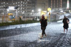 8月13日，暴雨席卷日本千叶县，人们走在雨水淹没的道路上缓缓前行。（法新社）