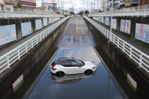 8月14日，日本千叶县镰谷市一处地下通道内，一辆汽车困在积水中无法动弹。（法新社）