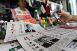 在中国首都北京，一名男子星期四（8月13日）在报摊购买商品，摊上陈列着刊登中国前总理朱镕基讣告的报纸。朱镕基在星期三（8月12日）逝世。（路透社）