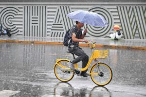 中国据报正考虑申办2028年第33届联合国气候变化大会（COP33）。图为北京一名男子8月15日在雨中骑着脚踏车。（法新社）